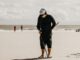 a man standing on a beach holding a baseball bat