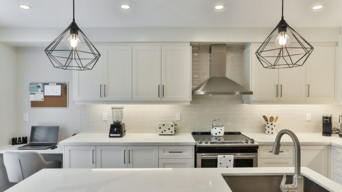 Photo by Lotus Design N Print white wooden kitchen cabinet with black pendant lamp