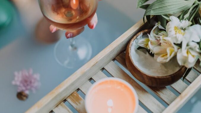 A serene bath setting with wine, candles, and flowers for a relaxing spa experience.